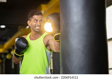 Aggressive Old Man In Sportswear Training With Boxing Bag In Gym