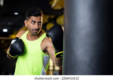 Aggressive Old Man In Sportswear Training With Boxing Bag In Gym