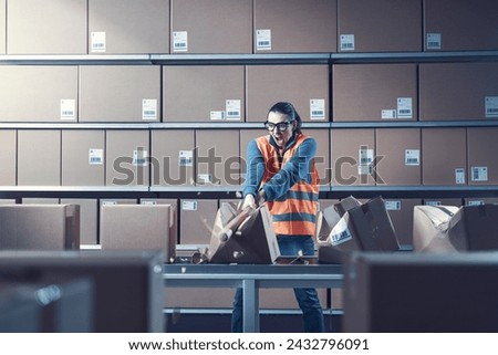 Aggressive rebellious warehouse worker smashing boxes at work, she is frustrated and angry
