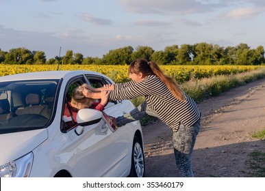 Aggressive Woman Pulling The Hair Of A Female Driver Inside A Car At The Driveway.