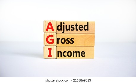 AGI adjusted gross income symbol. Concept words AGI adjusted gross income on wooden blocks. Beautiful white background, copy space. Business and AGI adjusted gross income concept.