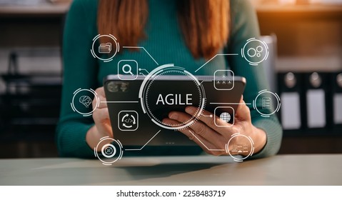 Agile development methodology concept. Business hand using laptop computer and tablet with virtual screen Agile icon on modern office digital technology concept. - Shutterstock ID 2258483719