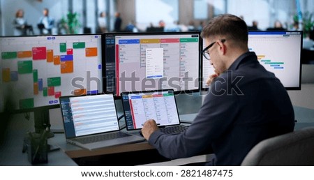 An Agile Project Manager Updates The Scrum Board Using Laptop And Tablet.
