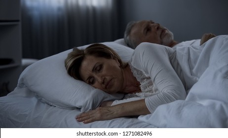 Aging husband and wife lying in bed awake, lady turned back to man, low potency - Shutterstock ID 1271082496