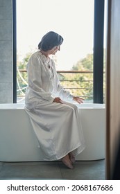 Aging Lady Checking Water Temperature In Bathtub