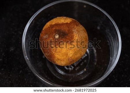 Aging process as seen on orange fruit placed in a glass bowl