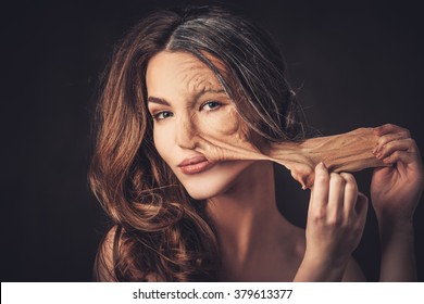 Aging And Skin Care Concept. Half Old Half Young Woman, Takes Off The Old Skin From The Face.