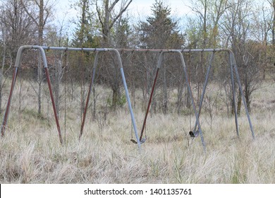 Aging swing set in a nature area with tall grass growing around it