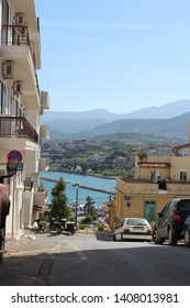 Agios Nikolaus/ Greece-04.30.2019: Amazing View Of A See And Mountains Thru The Street From The Top Of The Hill.