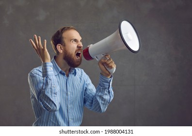 Agitated Young Man In Blue Shirt Shouting Loudly In Megaphone. Excited Salesperson, Office Worker Or Corporate Manager Yelling Like Crazy Announcing Start Of Mega Modern Business Products Sale