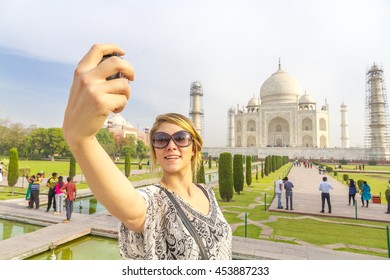 AGRA INDIA - CIRCA MAY 2016 - An unidentified tourist takes photos at the Taj Mahal at sunrise amidst a local crowd. 