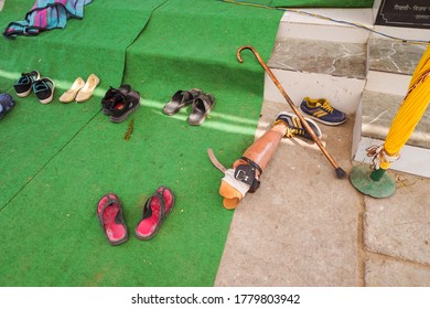 Agra / India - February 13, 2020: Orthopedic Leg And Shoes At The Foot Of The Entrance To A Small Hindu Temple In A Leper Village