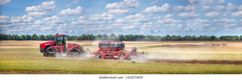 Agricultural Background With Red Tractor Pulling Plow, Throwing Dust In Air. Combine Harvester At Wheat Field. Heavy Machinery During Cultivation, Working On Fields. Dramatic Sky, Rain, Storm Clouds