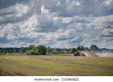 Agricultural Background With Red Tractor Pulling Plow, Throwing Dust In Air. Combine Harvester At Wheat Field. Heavy Machinery During Cultivation, Working On Fields. Dramatic Sky, Rain, Storm Clouds
