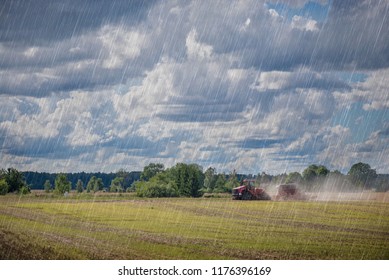 Agricultural Background With Red Tractor Pulling Plow, Throwing Dust In Air. Combine Harvester At Wheat Field. Heavy Machinery During Cultivation, Working On Fields. Dramatic Sky, Rain, Storm Clouds
