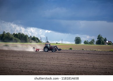 Agricultural Background. Tractor Pulling Plow, Throwing Dust In Air. Combine Harvester At Wheat Field. Heavy Machinery During Cultivation, Working On Fields. Dramatic Sky, Sun Rays, Rain, Storm Clouds