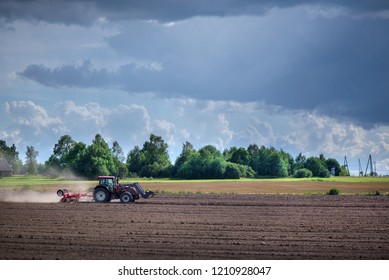 Agricultural Background. Tractor Pulling Plow, Throwing Dust In Air. Combine Harvester At Wheat Field. Heavy Machinery During Cultivation, Working On Fields. Dramatic Sky, Sun Rays, Rain, Storm Clouds