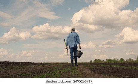 Agricultural business, Farmer businessman works in spring on plowed land with shovel, bucket. Farmer uses shovel and bucket to grow crop, vegetable field. Harvesting vegetables. Agricultural industry