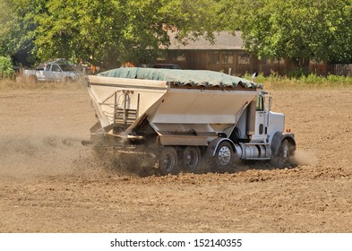 Agricultural fertilizer spreader working a newly plowed field in preparation for a new vineyard