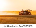 Agricultural harvester harvesting in the field at sunset. Harvesting with agricultural machinery. Agribusiness.