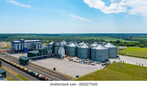 Agricultural Industry. Modern Factory On Green Field With Steel Elevators. Industrial Buildings And Granary Under Blue Sky. Aerial View