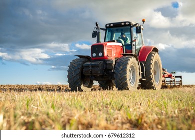agricultural machinery in the foreground carrying out work in the field - Shutterstock ID 679612312