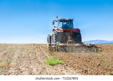 agricultural machinery in the foreground carrying out work in the field - Shutterstock ID 713267893