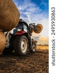 An agricultural tractor loader loads bales of hay on the field. Agricultural telescopic handler harvesting straw.