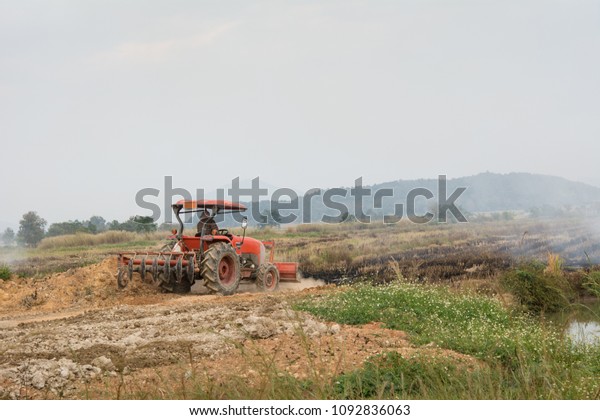 Agricultural\
worker with tractors on the burning\
fields