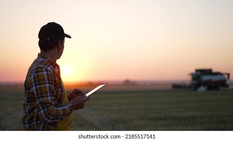 Agriculture. Agronomist senior stands with tablet in wheat field, harvests in background. combine harvests wheat on farmer's field. Agronomist senior with tablet. man in agriculture - Shutterstock ID 2185517141