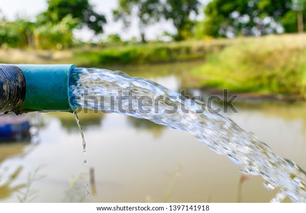 Agriculture\
blue pipe with groundwater gushing in\
pond