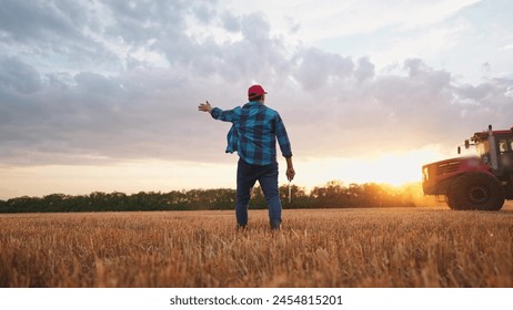 agriculture. farmer walk works in field next to a tractor that plows the land. business agriculture concept. farmer with tablet works in a field next to a tractor at sunset mowed farm wheat plows - Powered by Shutterstock