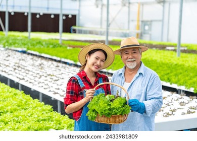 Agriculture industry, hydroponic system and organic healthy food eating concept. Portrait of Happy Asian farmer holding organic lettuce vegetable in basket at hydroponics system greenhouse garden. - Powered by Shutterstock