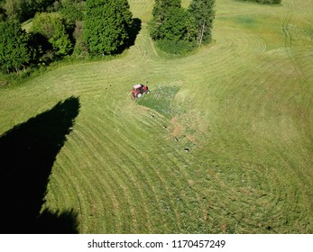 Agriculture old tractor cut hay grass on midsummer meadow, aerial view  