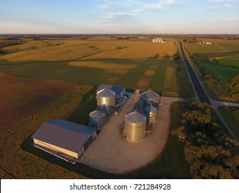 Agriculture photo taken in early fall with grain bins and buildings casting shadows onto fields of beans and corn.