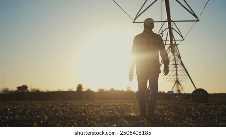 Agriculture. Silhouette of a farmer irrigating his corn. Agriculture field farm concept. Farmer goes to install irrigation. Silhouette of a farmer going for lifestyle irrigation with corn. - Powered by Shutterstock