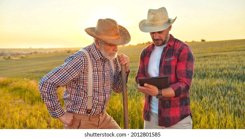 Agriculture technology of quality control. Two confident farmers monitoring harvest growth progress via tablet. Data collection and analyzing by artificial intelligence. Future agro crops concept