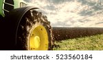 Agriculture. Tractor plowing field. Wheels covered in mud, field in the backround. Cultivated field. Agronomy, farming, husbandry concept.