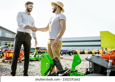 Agronomist Shaking Hand With Salesman, Having A Deal About Purchase A New Agricultural Machinery On The Outdoor Ground Of The Shop