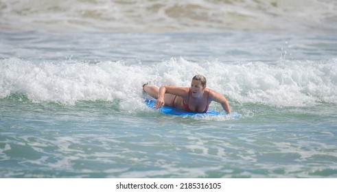 Ahangama, Sri Lanka - 04 17 2022: An Old Woman Bodyboarding On The Beach, An Old Mature Lady Lying On The Surfboard And Riding Forward With A Small Wave. Enjoying The Vacation On A Tropical Island.