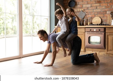 Ahead on horse. Caring young father giving horseback ride to little daughter son playing at home on weekend. Cute brother sister kids sitting on back of dad crawling around on kitchen wooden floor - Powered by Shutterstock