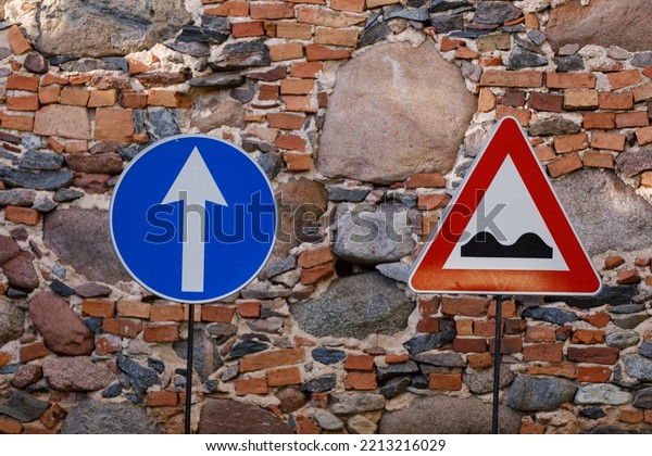 Ahead only sign and uneven road sign with a\
stone and brick wall\
background