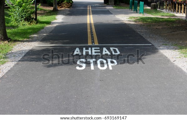 The ahead stop painted white on the foot path at\
the park.