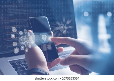 AI, Artificial Intelligence, Big data, Internet of Things IoT. Man, programmer, software engineer using mobile smartphone by id touch on screen, coding on laptop computer with technology background - Powered by Shutterstock