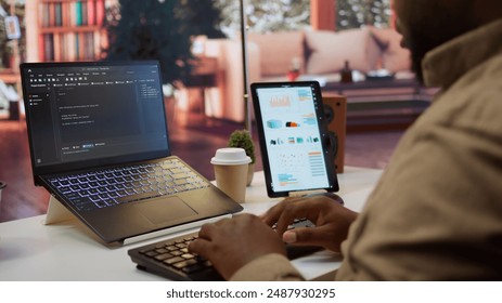 AI software developer creating an algorithm for deep learning and data mining, coding on his laptop at home office. Expert processing binary code on supercomputer neural network. Camera B.