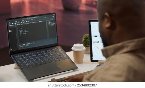 AI software developer creating an algorithm for deep learning and data mining, coding on his laptop at home office. Expert processing binary code on supercomputer neural network. Camera A.