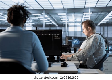 AI technician at work in high tech server room analyzing data on monitors, ensuring seamless data flow. Man in artificial intelligence data center, ensuring system integrity and security