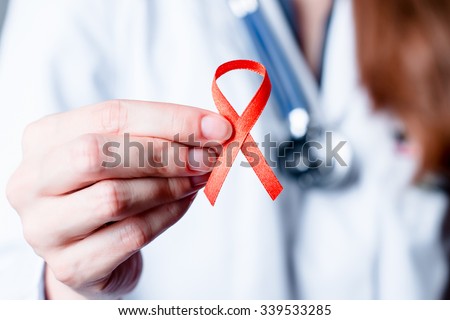 AID, HIV red ribbon. Symbol of awareness, charity, support in disease, illness, ill. Medical health care, help and hope. Sign of healthcare medicine campaign holding in female doctor hand.  