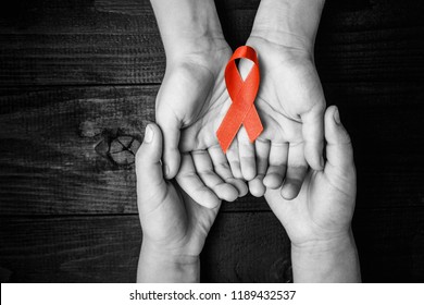 AID red ribbon in hand on a black wooden background, a symbol of the fight against HIV, AIDS and cancer. concept of helping those in need. black and white.
