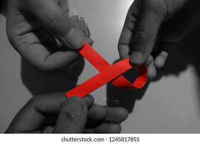 Aids Red Ribbon On Woman's Hand Support For World Aids Day And National HIV/AIDS And Aging Awareness Month Concept